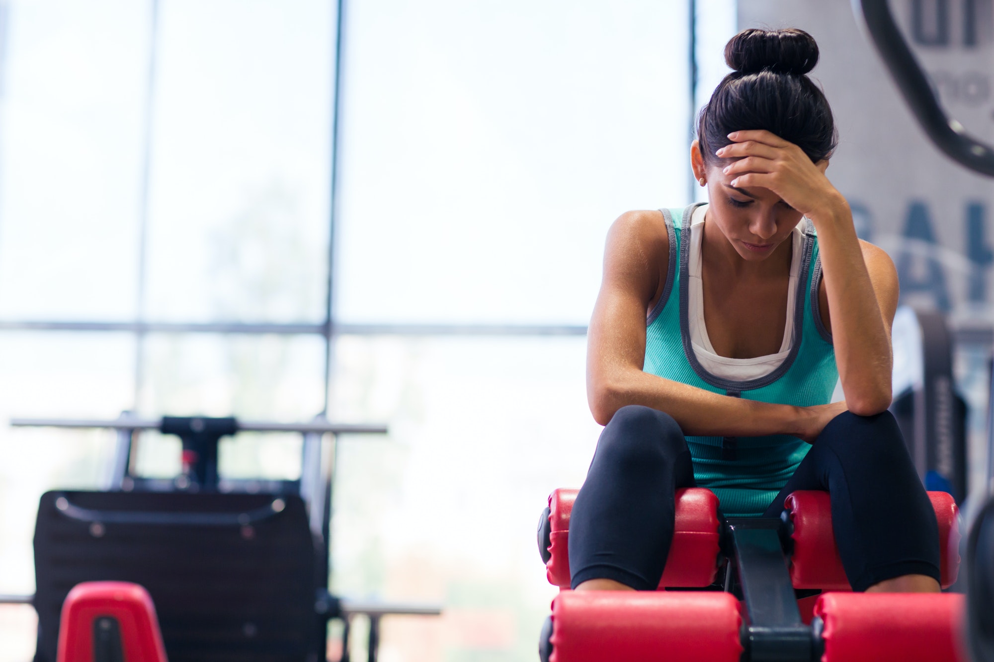 Tired woman sitting on exercises machine 90 day 3 month body transformation