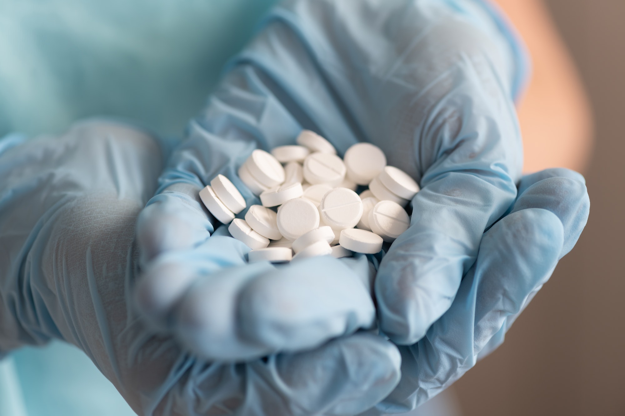 Closeup doctor or nurse hands in blue rubber gloves with handful pills Closeup doctor or nurse hands in blue rubber gloves with handful pills
