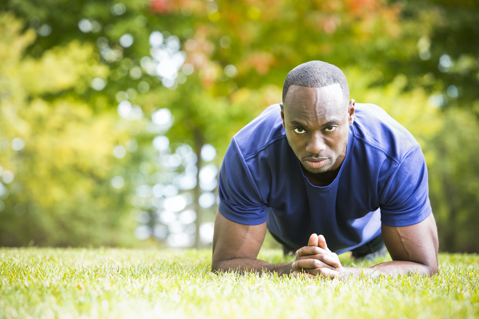 Fit man doing plank core exercise in the park