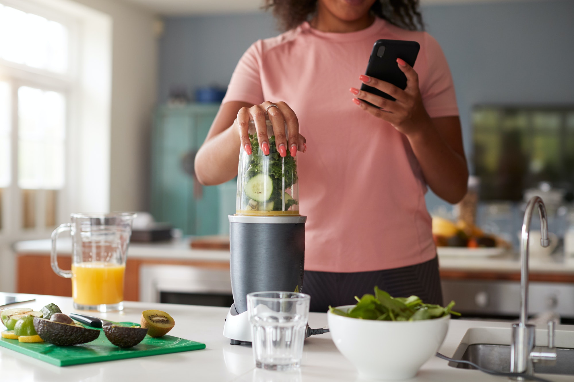 Close Up Of Woman Using Fitness Tracker To Count Calories For Post Workout Juice Drink She Is Making