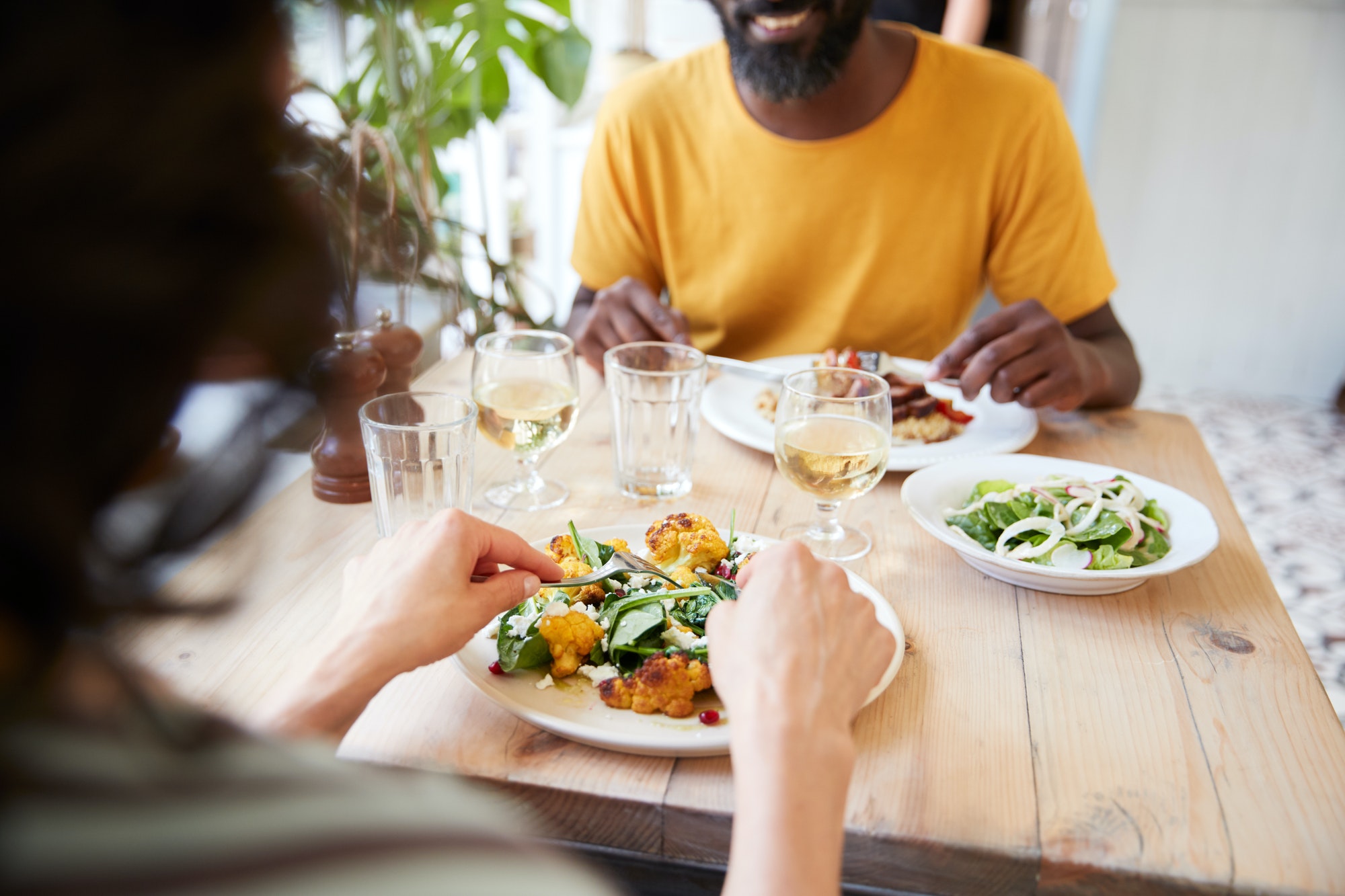 Couple eating at restaurant, over shoulder view, mid section