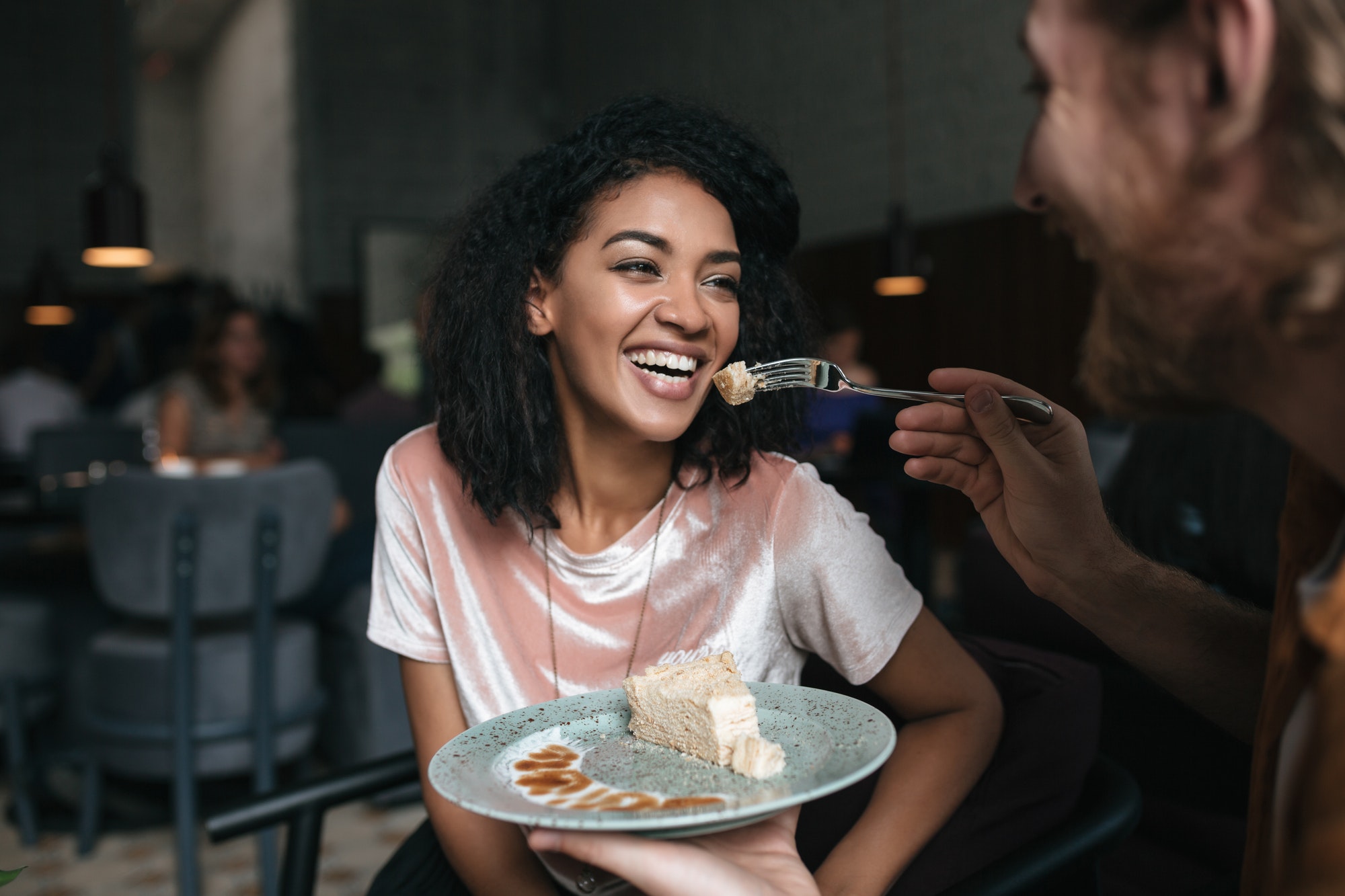 Joyful couple eating dessert and having fun time at the cafe