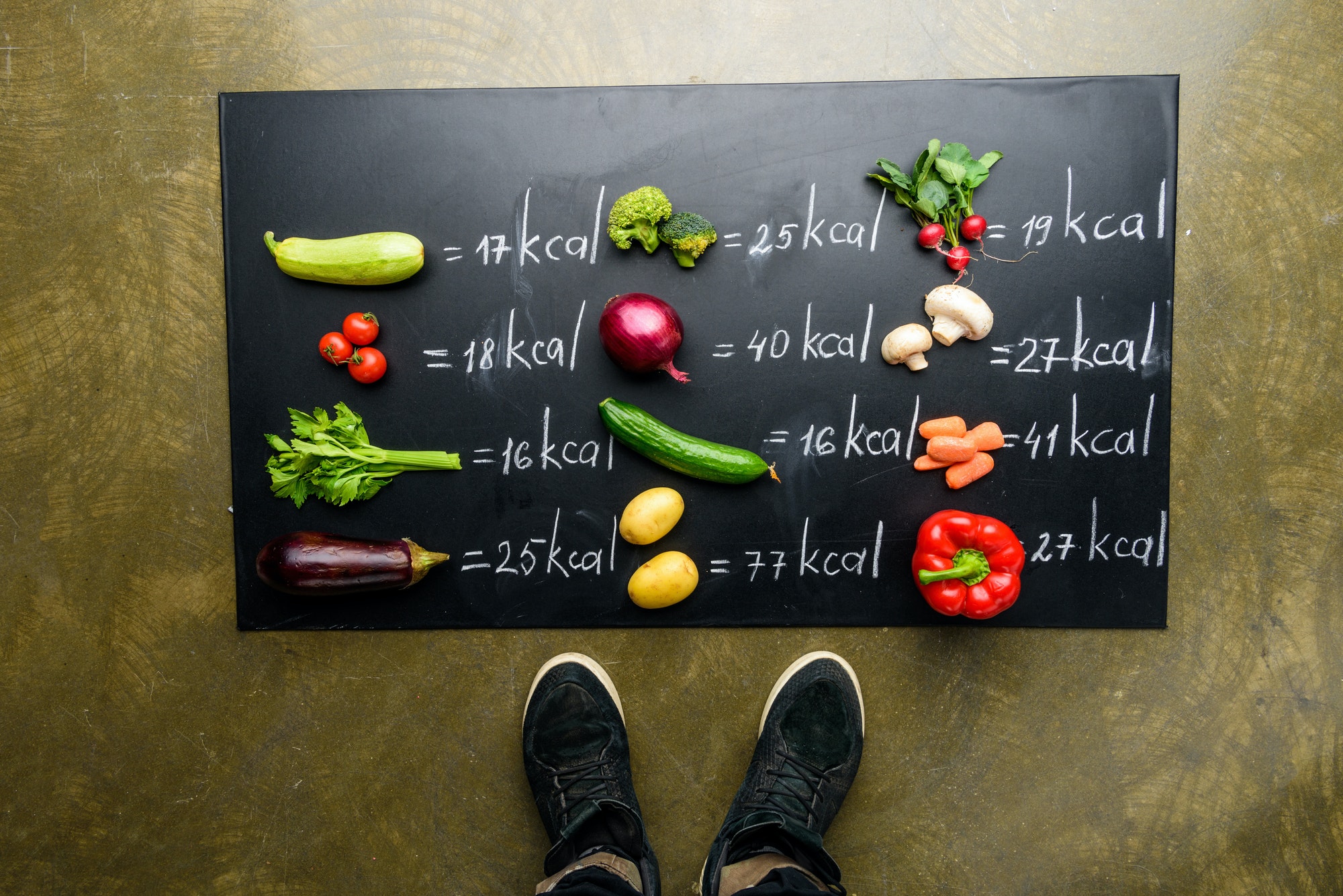 partial view of man standing near fresh vegetables and calories table, healthy lifestyle concept